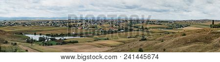 A Typical Natural Landscape In The Country Of Suceava: Fields, A Small Lake And A Village Of Houses 