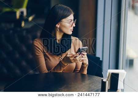 Brunette Girl Using Her Cell Phone While Sitting At A Rastaurant For Lunch