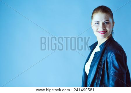 portrait of beautiful young brunette woman in stylish black jacket on gray.