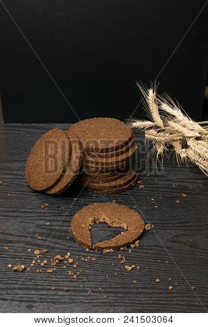 Round Slice Gallets Of Black Bread With A Cut In The Shape Of A Heart On Dark Wooden Background. Vie