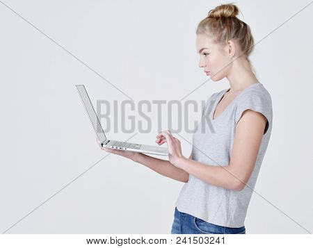 Young woman holds laptop in habds.  Calm caucasian girl with notebook posing at studio