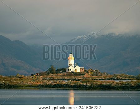 Famous Isle Ornsay With  Lighthouse Tower, Isle Of Skye, Scotland, Uk. Snowy Mountains In Background