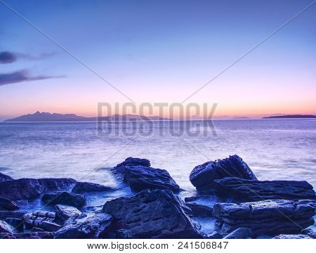 The Stony Beach And Cliff Of Rocky Bay. Blue Tones Of February Sunset, Pink Horizon.  Dark Slipery B