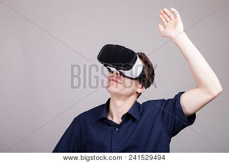 Excited Man Experiencing Virtual Reality For The Firts Time. He Is Wearing A Vr Headset. Gray Backgr