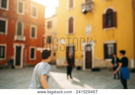 Blur Background With Three Teens Playing Ball In The Yard. Vinice, Italy.