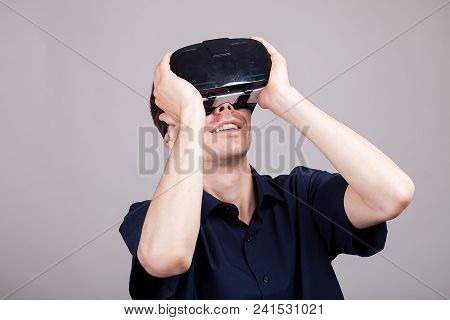 Excited Man Experiencing Virtual Reality For The Firts Time. He Is Wearing A Vr Headset. Gray Backgr