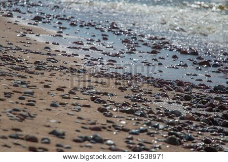 Beautiful Smooth Sea Stones In The Sands Of The Beach. Closeup Photo Of Stone Textures And Shapes.