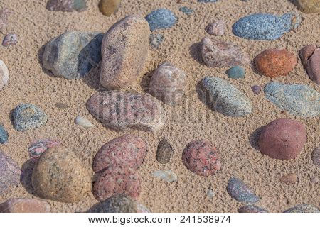 Beautiful Smooth Sea Stones In The Sands Of The Beach. Closeup Photo Of Stone Textures And Shapes.