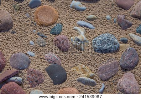 Beautiful Smooth Sea Stones In The Sands Of The Beach. Closeup Photo Of Stone Textures And Shapes.