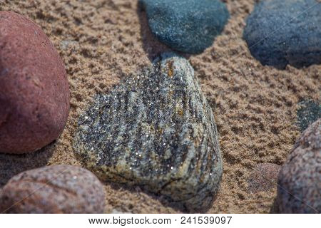 Beautiful Smooth Sea Stones In The Sands Of The Beach. Closeup Photo Of Stone Textures And Shapes.