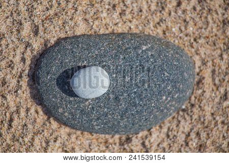 Beautiful Smooth Sea Stones In The Sands Of The Beach. Closeup Photo Of Stone Textures And Shapes.