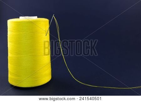 Yellow Skein Of Thread With A Needle On A Blue Background