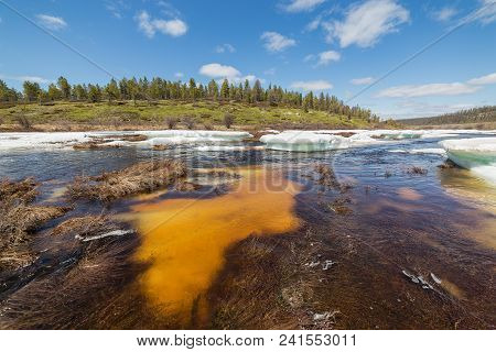 Spring Landscape On The Creek With Turquoise Ice Floes, Underwater Ice Orange And Green Hills On A F