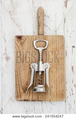 A Corkscrew On A Vintage Cutting Board Over White Wooden Table With Copespace, Flatlay. Wine Degusta