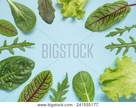 Frame Of Fresh Leaves Of Green Spinach And Arugula Salad Rocket, Arugula On A Blue Background