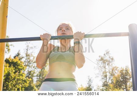 Fit Woman Doing Pull-ups. Young Athletic Fitness Woman Working Out At Outdoor Gym Doing Pull Ups At 