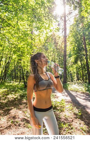 Young Woman Drinking Water After Running Outdoors.