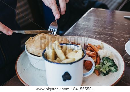 Man Sitting At The Wooden Table, Eating Pie And Chips, Traditional English Dish.
