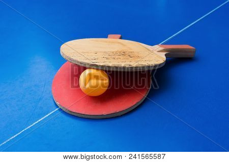 Old Pingpong Rackets And A Dented Ball On A Blue Pingpong Table