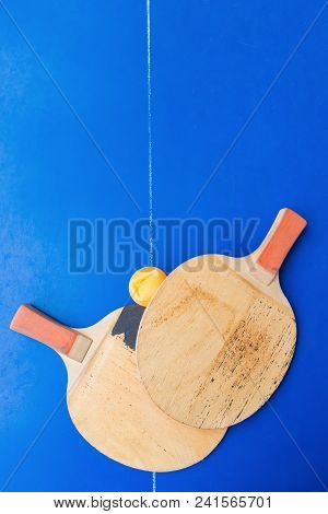 Pair Of Old Pingpong Rackets And A Dented Ball On A Blue Pingpong Table