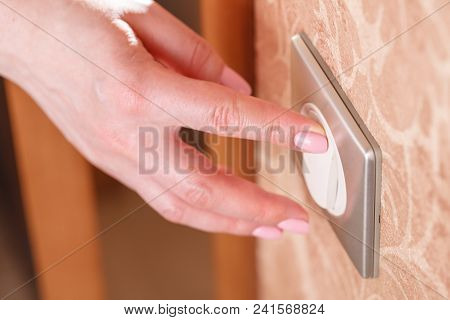 Hand Presses The Light Switch On The Wall