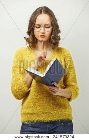 Puzzled Woman Looking At Diary With Disgruntled Expression, Demonstrating Frustration Or Complexity 
