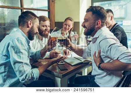 Young Cheerful People Smile And Gesture While Relaxing In Pub. Team Job. Photo Young And Mature Busi