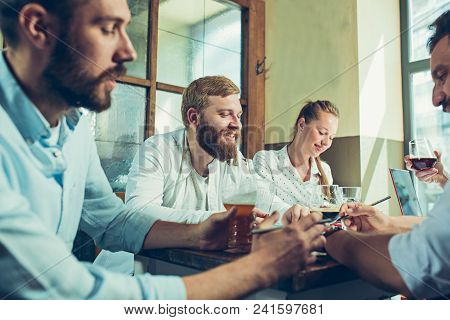 Young Cheerful People Smile And Gesture While Relaxing In Pub. Team Job. Photo Young And Mature Busi