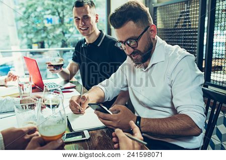 Young Cheerful People Smile And Gesture While Relaxing In Pub. Team Job. Photo Young And Mature Busi