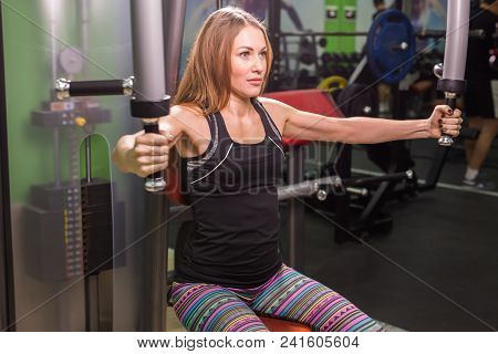 Pretty Caucasian Smiling Woman Is Working Out On Butterfly Machine In Gym