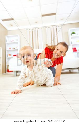 Lächelnd Mommy mit kriechend am Boden Baby spielen