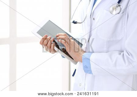 Woman Doctor Using Tablet Computer While Standing Straight In Hospital Closeup. Healthcare, Insuranc