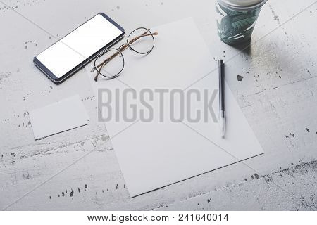 Mockup Of Blank Sheet Paper, Smartphone, Eye Glasses And Two Empty Business Cards On White Wooden De