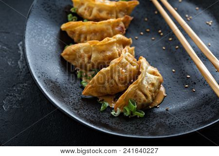 Fried Potstickers With Green Onions On Black Plate