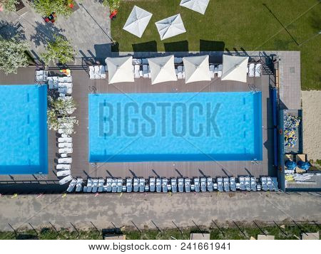 Swimming pool blue water and white beach beds on the garden