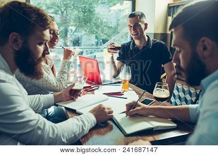 Young Cheerful People Smile And Gesture While Relaxing In Pub. Team Job. Photo Young And Mature Busi