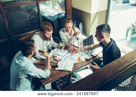 Young Cheerful People Smile And Gesture While Relaxing In Pub. Team Job. Photo Young And Mature Busi