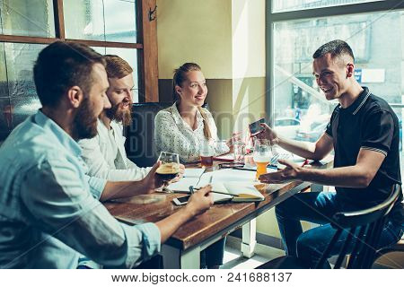 Young Cheerful People Smile And Gesture While Relaxing In Pub. Team Job. Photo Young And Mature Busi