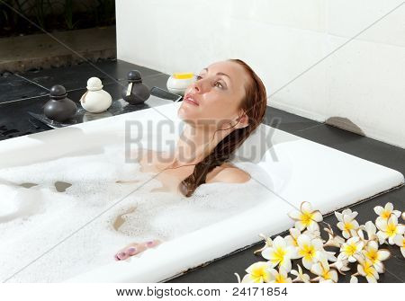 ผู้หญิงวางใน soapsuds ในการอาบน้ำที่เต็ม