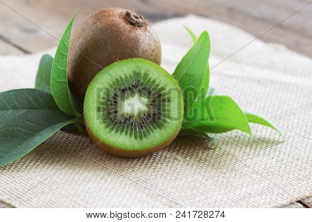 Fresh And Juicy Whole Kiwi Fruit And A Half On Wood Table. Ripe Kiwi In Side View With Copy Space Fo
