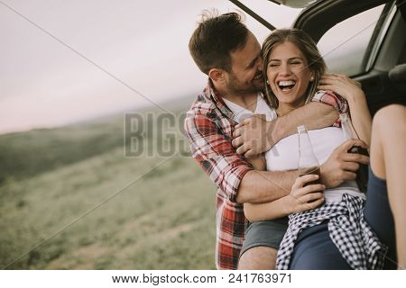 Loving Couple Sitting In The Car Trank