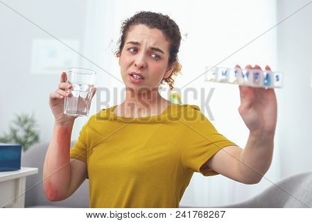 Treatment Mistake. Young Woman Holding A Pill Container Looking Annoyed Having Missed One Day Of Tak