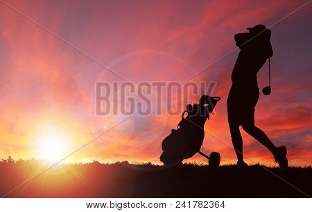 Silhouette Of Golfer With Golf Bag By His Side Swinging Club Toward Sunset With Deliberate Lens Flar