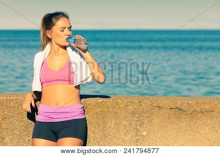 Woman In Sportswear Takes A Break To Rehydrate Drinking Water From Plastic Bottle, Resting After Spo