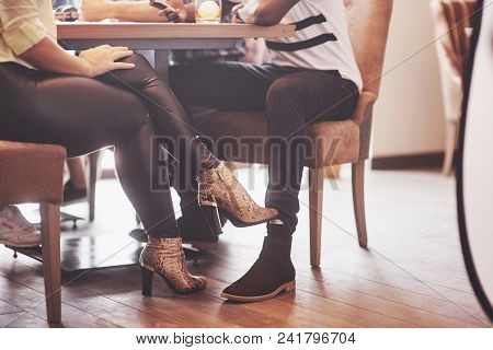 Girl Flirting With A Guy Touching Leg Her Foot Under The Table In A Cafe While Having Fun With The F