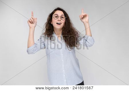 Young Girl With Glasses On A Gray Background. Portrait Of A Young Beautiful Girl. A Charming Girl In