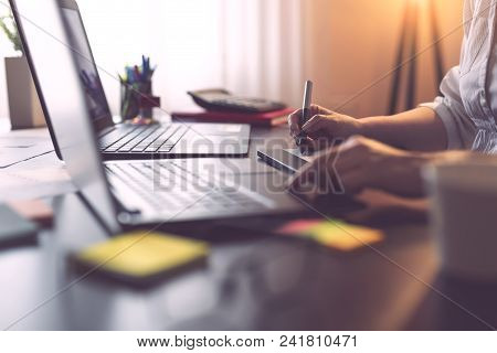 Detail Of A Designers Hand Holding A Pen And Drawing On A Graphic Board. Focus On The Tip Of The Pen
