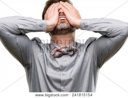 Middle age man, with beard and bow tie stressful keeping hands on head, tired and frustrated isolated over white background