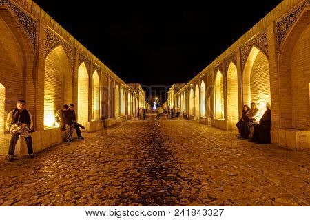 Isfahan, Iran - May 7, 2015: People Walking And Socializing On The Ancient Khaju Bridge By Night.