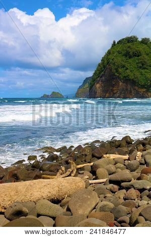 Waves Crashing Onshore To A Rural Rocky Beach Surrounded By Mountain Bluffs With Lush Tropical Fores